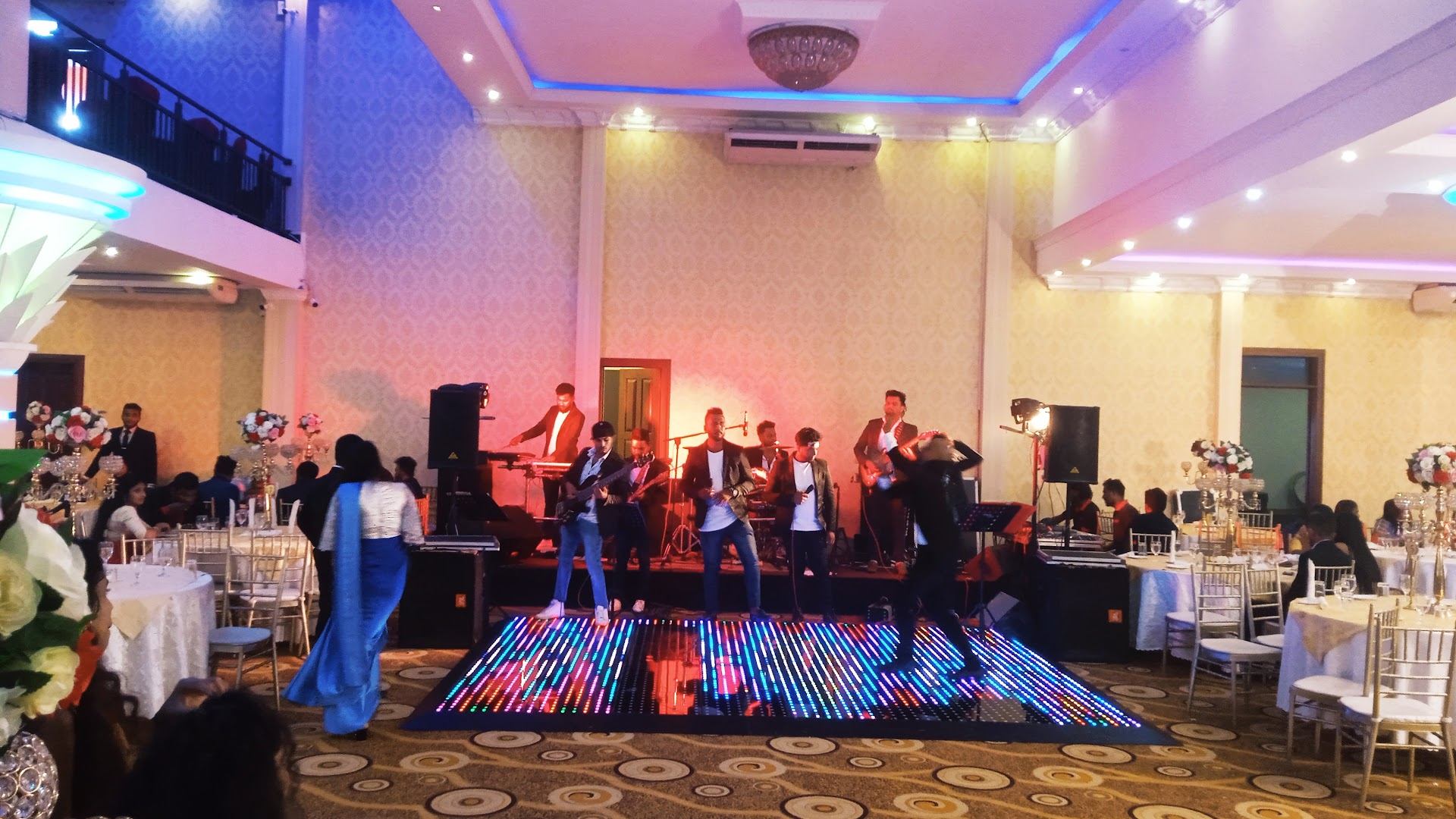 A live band playing behind the light-up dance floor while guests dance