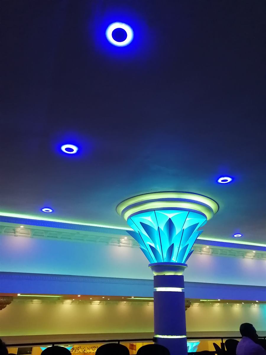 A lotus-crowned pillar glowing under the hall's ceiling lights